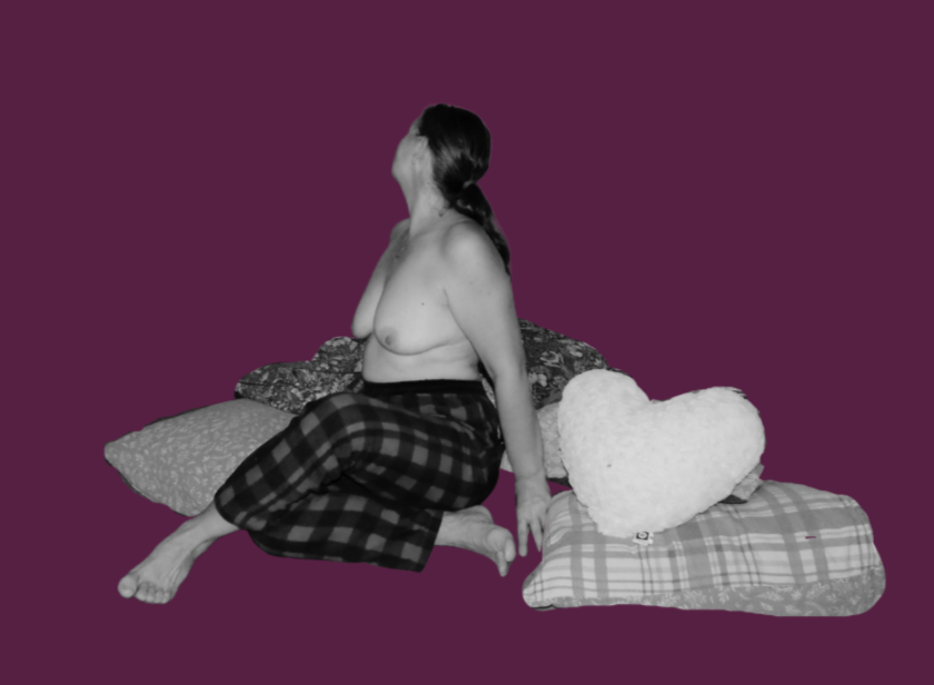 Portrait artistique en noir et blanc sur fond bordeaux, une femme assise parmi des coussins avec un coussin en forme de cœur